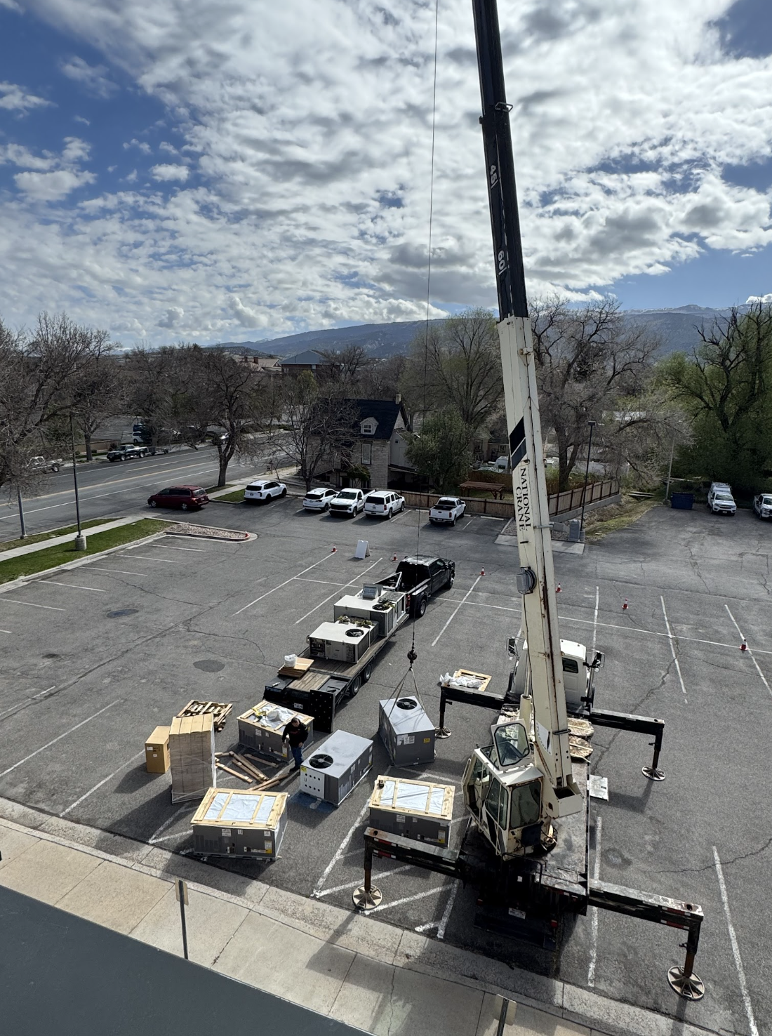 Commercial HVAC units being installed with a crane in a parking lot
