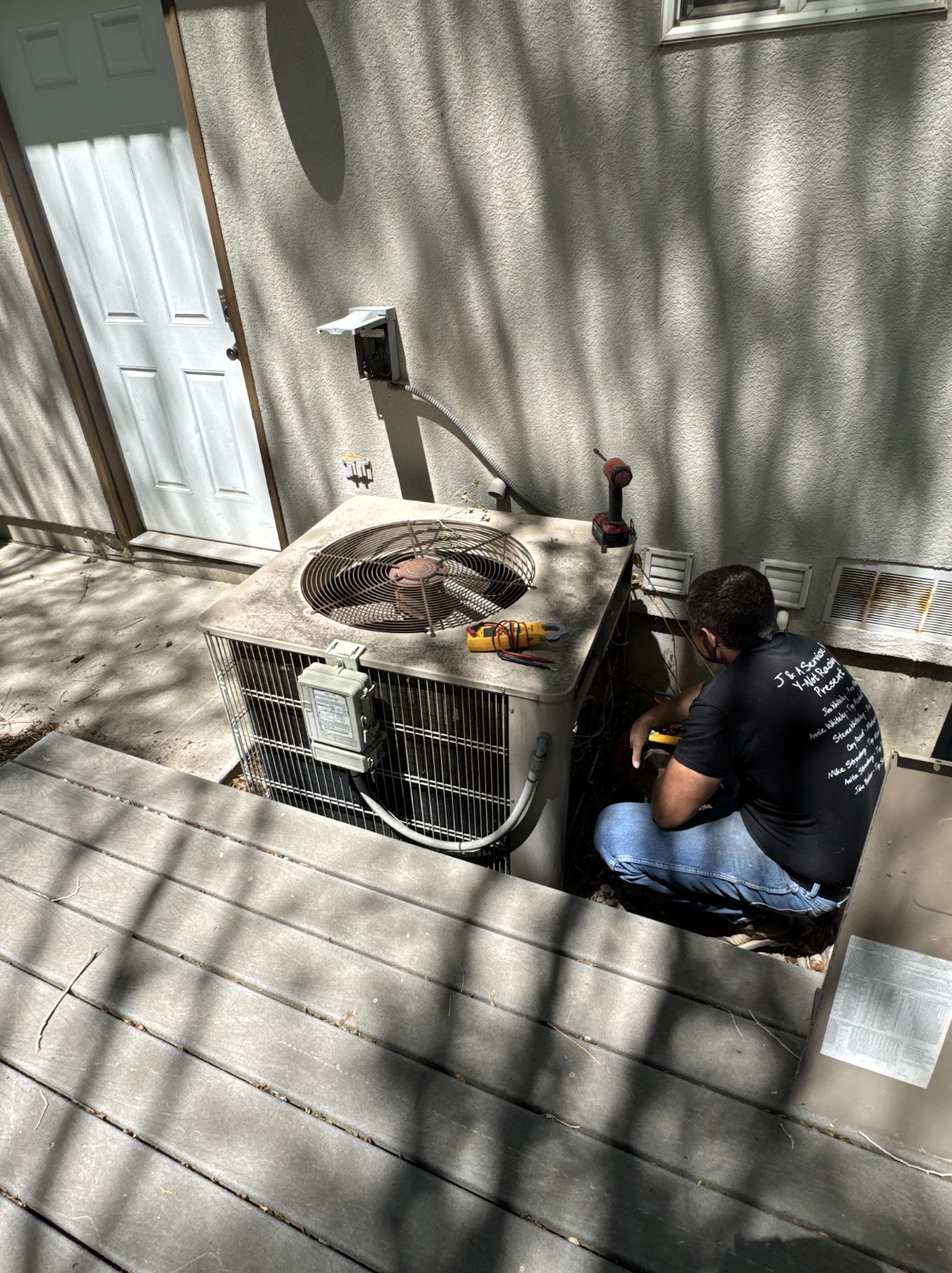 Technician servicing an outdoor air conditioning condenser unit