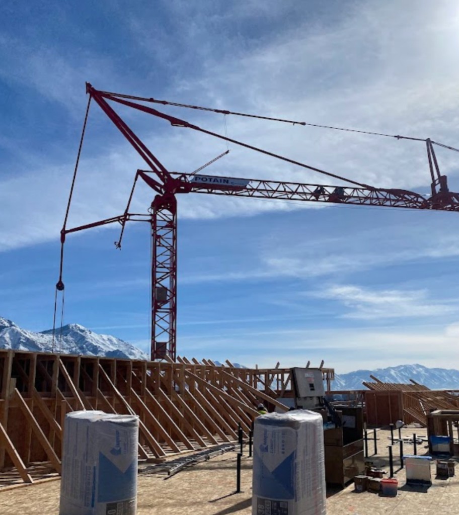 Large-scale commercial building construction with tower crane and insulation materials