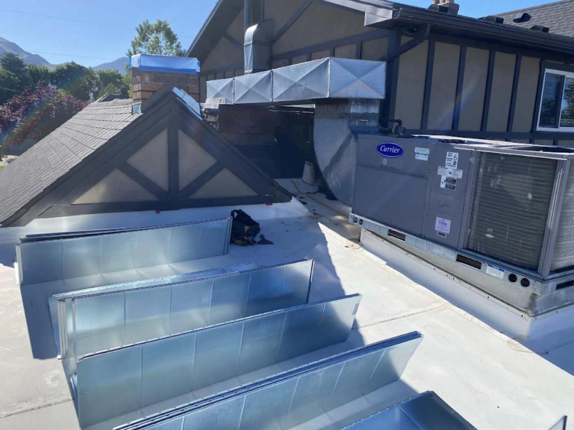 Custom fabricated sheet metal ductwork connected to a rooftop Carrier HVAC unit