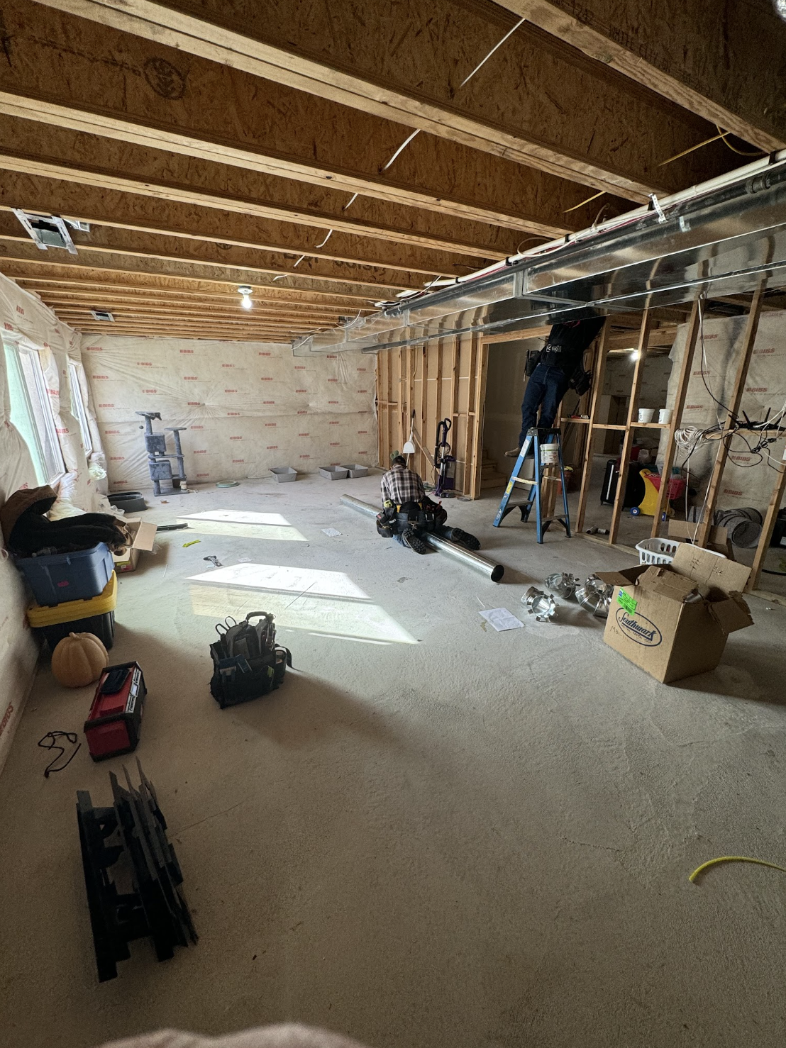 Technicians installing basement ductwork during an HVAC remodel