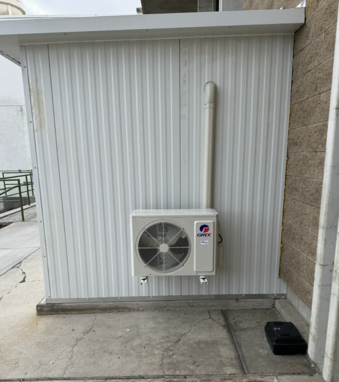Gree outdoor mini-split condenser unit wall-mounted on corrugated metal siding