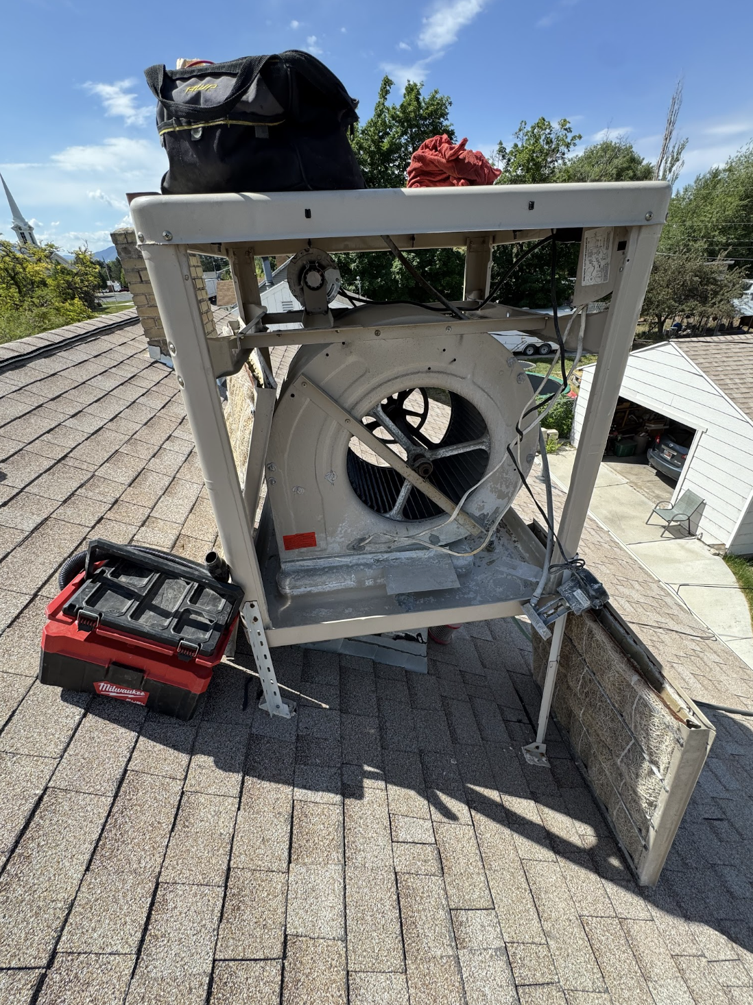 Technician servicing a rooftop swamp cooler with panels removed