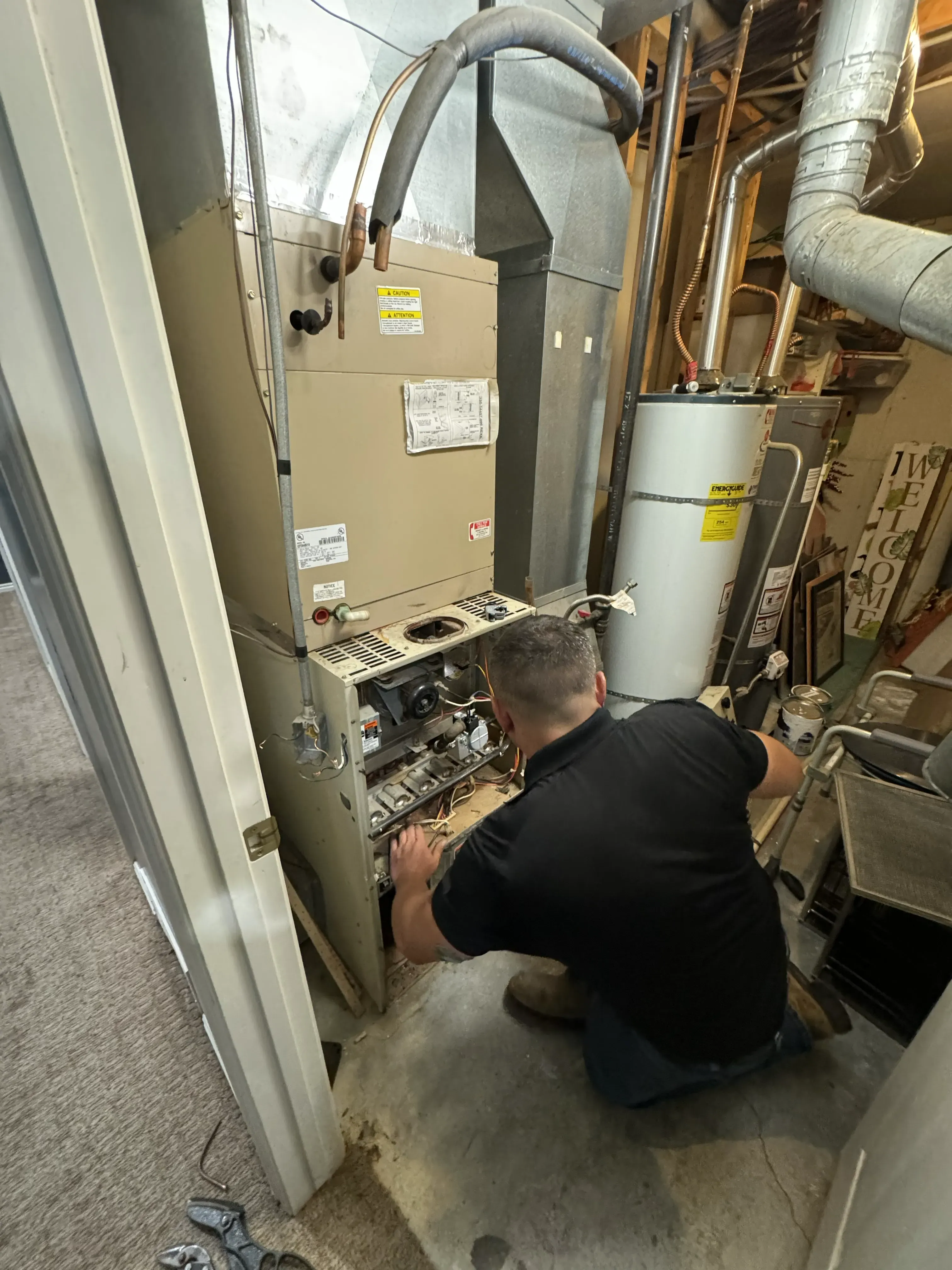 Technician repairing furnace in a utility closet